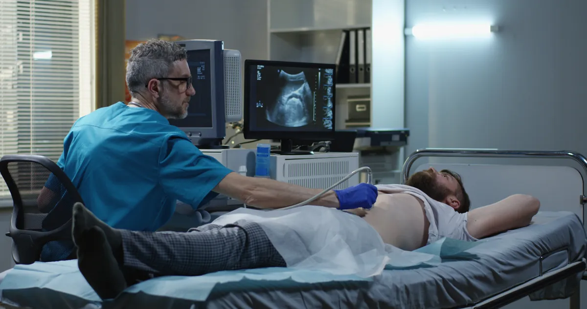 A sonographer carrying out an ultrasound scan of a man's abdomen