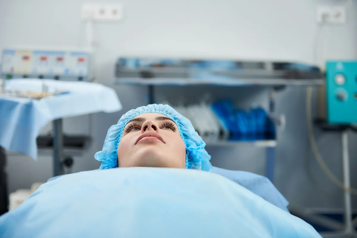 A patient in a surgical cap lying on an operating table before surgery